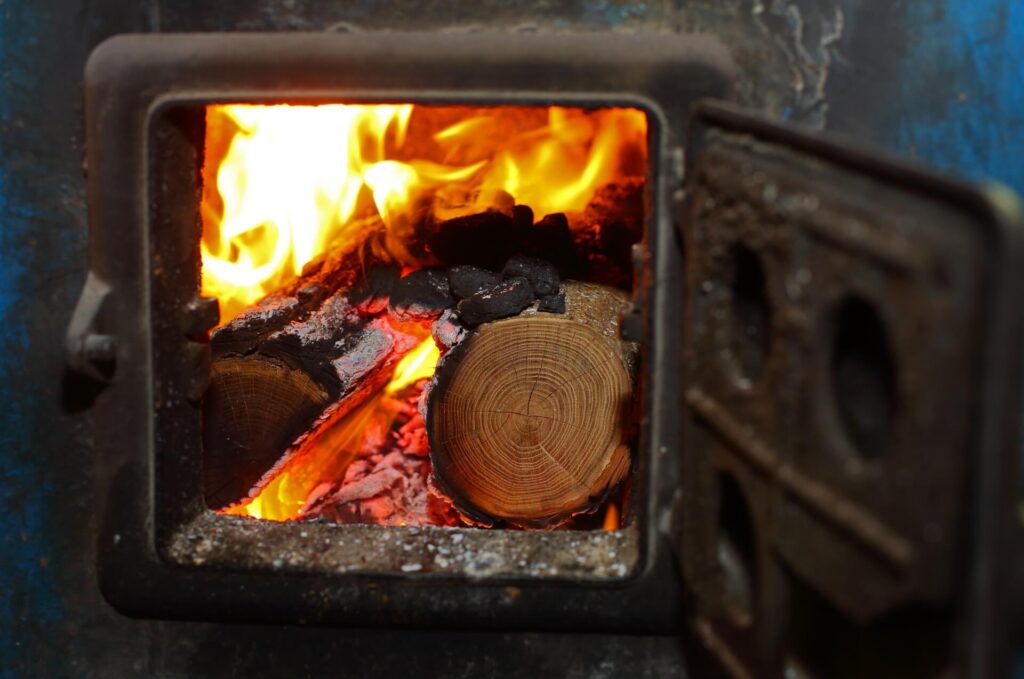 View of the inside of a wood burning stove filled with wood and fire